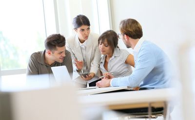 Vier Personen besprechen ein Projekt gemeinsam am Laptop